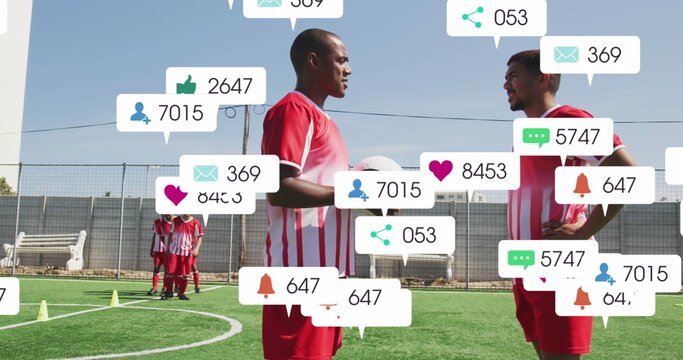 Social media icons over two diverse male soccer players talking to each other on sports field - Powered by Adobe