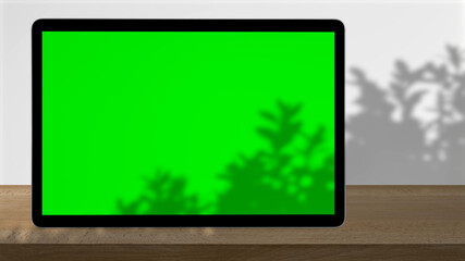 Tablet with green screen outdoors, trees swaying in the background.
