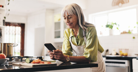 Cooking, phone and reading of woman in kitchen to search for ingredients or instructions of recipe....