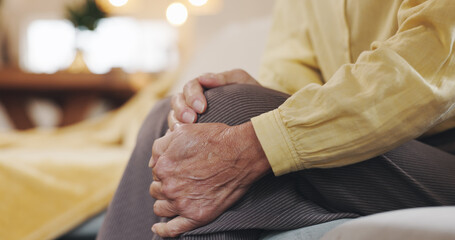 Obraz premium Hands, inflammation and knee pain with mature person on sofa in living room of home for arthritis. Accident, emergency or joint injury and senior in apartment with osteoarthritis or tendinitis