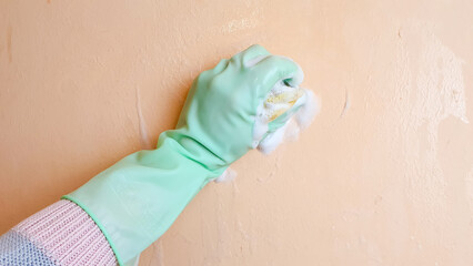Washing the walls, cleaning the surface with a sponge and foam. The woman cleans the room.