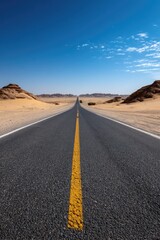 A asphalt road cutting through a vast desert landscape, surrounded by endless stretches of sand dunes under a cloudless, bright blue sky