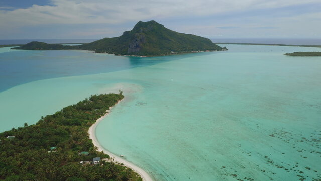 Fototapeta Aerial view of Bora Bora lagoon showing mount Otemanu, lush tropical vegetation, turquoise water, coral reef, and white sand beach in French Polynesia
