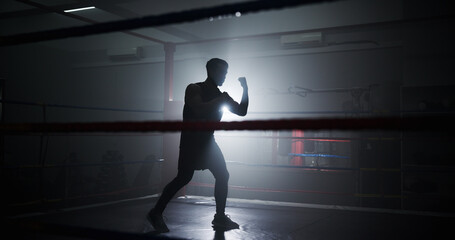 Person, silhouette and boxing in ring with punch, training and power with routine for combat...