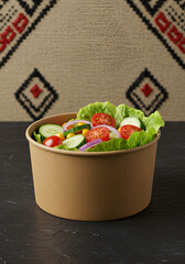 Fresh vegetable salad in a paper bowl