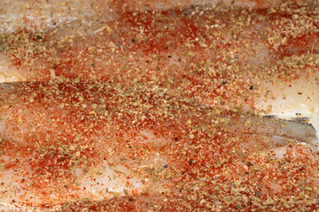 Close up of seasoned and herb fish waiting to be cooked