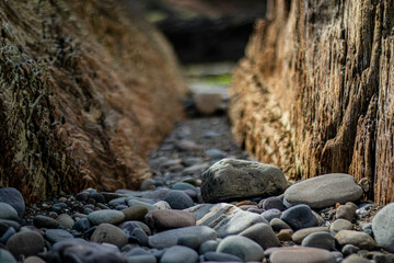 Passage between two layered rocks on the coast with focus on the rocks in the foreground, Irish Cliffs