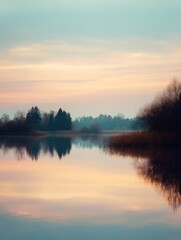 Fototapeta premium Tranquil Reflection of Soft Sunrise Hues Over Calm Water Surrounded by Forest and Reeds in a Serene Landscape