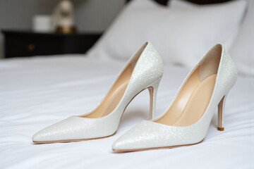 pair of white wedding shoes sitting on top of a bed