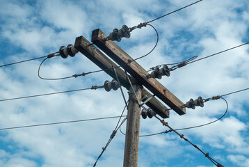 Wooden electric pole reinforcement with steel ropes in blue sky closeup