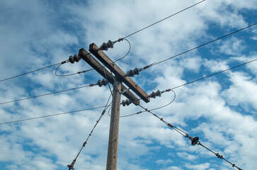 Wooden electric pole reinforcement with steel ropes in blue sky closeup