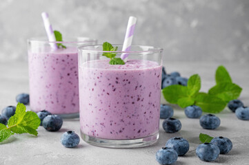 Smoothie with blueberries, banana, chia seeds and yogurt in a glass on a gray concrete background....
