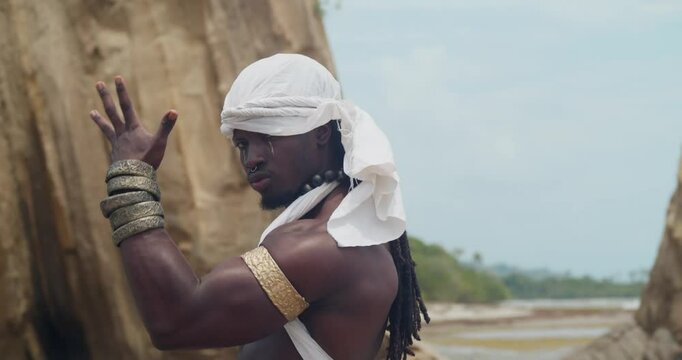 Displaying muscles and dark skin, a male cosplayer on the beach.