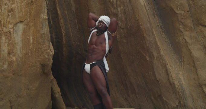 On the sandy shore, a muscular male cosplayer with dark skin.