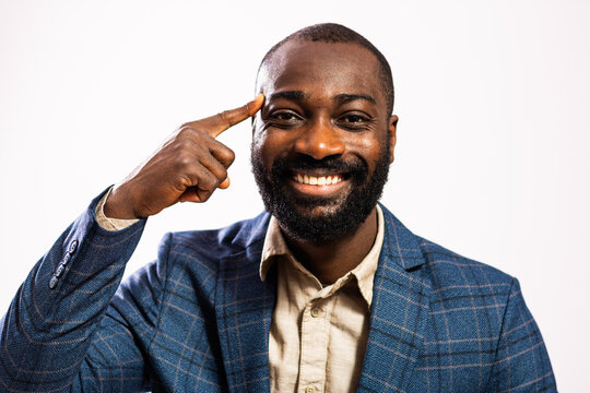 Portrait of happy and successful businessman. Black man in business suit is pointing at his head. He is having inspiration.