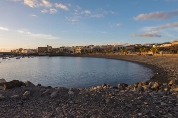 Golden sunset view of Playa de San Juan bay with protected sand beach and small harbor. Playa de San Juan is a small fishing village on the south west of Tenerife island.