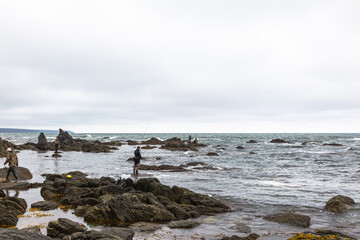 Cape Ostry. A small group of unknown fishermen on the shore. South Sakhalin, Russia