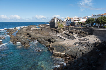 View of old fishing village Garachico with sea pools and lava rocks village center in Tenerife canary island spain with blue sky white clouds background