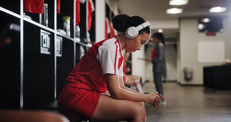 Woman, soccer player and headphones in locker room for music, sports and inspiration for game. Profile, girl and athlete with streaming, listen and prepare with audio subscription for football match