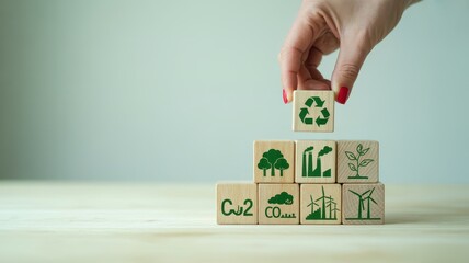 Hand placing a wooden block with a recycling symbol on a stack of blocks.