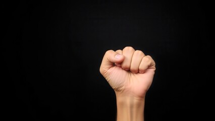 Fototapeta premium A clenched fist on a dark background symbolizes strength, unity and determination. The image is powerful and laconic. Suitable for themes of leadership, protest and motivation.