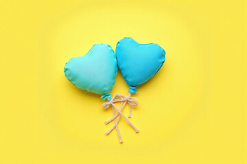 two blue heart shaped balloons on a yellow background
