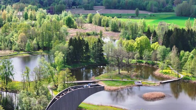 A Scenic View From the Kirkilai Observation Tower Reveals Winding Boardwalks, Tranquil Karst Lakes, and Lush Forested Surroundings in Biržai Regional Park, Lithuania - Aerial Pullback Shot