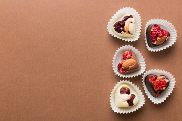 chocolate sweets in the form of a heart with fruits and nuts on a colored background. top view with space for text, holiday concept