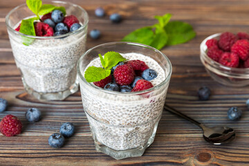 Healthy breakfast or morning with chia seeds vanilla pudding raspberry and blueberry berries on table background, vegetarian food, diet and health concept. Chia pudding with raspberry and blueberry