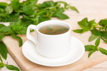 Cup of mint tea on table background. Green tea with fresh mint top view with copy space