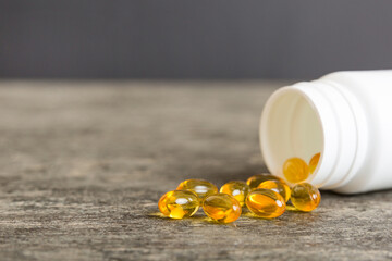 Soft gels pills with Omega-3 oil spilling out of pill bottle close-up. Gel capsules bottle white...