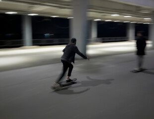 A man rides a skateboard along an empty street at night, capturing a sense of freedom and movement...