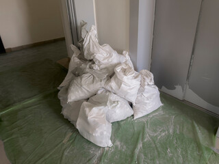 Bags of construction waste are piled together in an apartment, indicating ongoing renovation and...