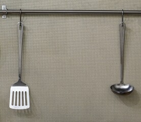 tableware on kitchen with ladles serving spoon and spatula for cooking hanging in the kitchen above...