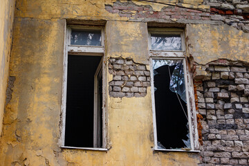 Broken windows in an old abandoned building, damaged brick facade