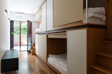 Modern hostel with cozy minimalist dorms, wooden capsule beds, and peaceful courtyard. Men chatting and relaxing in a quiet neighbourhood