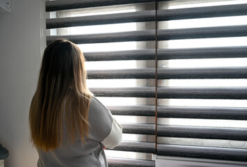 Depressed woman looking out the window. Anxious girl in the apartment. Emotional crisis. A sad and worried female.
