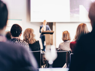 Speaker giving a talk in conference hall at business event. Rear view of unrecognizable people in...