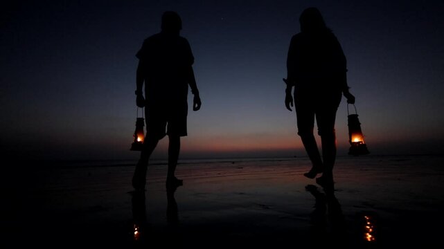 A couple walks hand in hand along the beach, a lantern casting a warm glow as the sun sets. The sky is painted in hues of orange and pink, reflecting off the gentle waves. Their silhouettes merge with