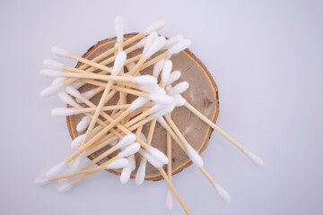 A pile of natural bamboo cotton swabs scattered on a rustic wood slice against a soft background. Choose eco-friendly essentials for a gentle routine