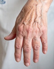Fototapeta premium A poignant close-up of an elderly person's hand, with visible wrinkles, veins, and age spots, showcasing the passage of time