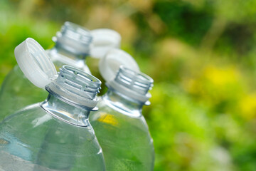 Plastic bottles with so-called tethered caps against a green blurry background. The caps are attached to the drink bottle to prevent it from ending up in nature. The EU bans loose closures and caps.