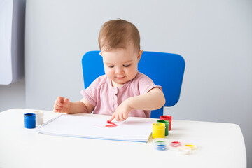 child is drawing on white sheets with finger paints