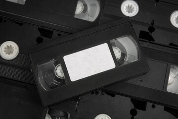 Stacked VHS tapes with a blank white label, black cassette.