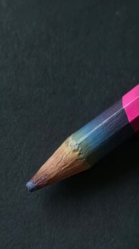Close-up of a sharpened multicolored drawing pencil on dark textured background, showcasing its tip, and wood grain textures, artistic tool for creative expression
