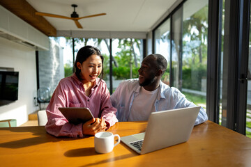 Multiethnic freelancer couple enjoy the environment of tropical climate, working on laptop together