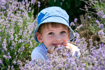 Close portrait of happy child in lavender field wearing blue hat and smiling