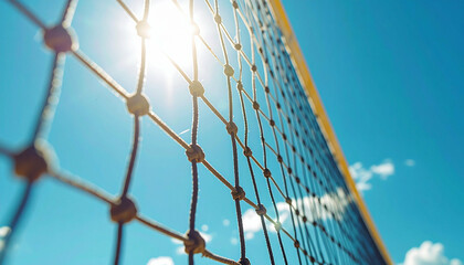 Volleyball net against bright sun and a blue sky with soft white clouds