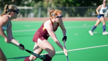 A skilled female field hockey player showcases her offensive prowess as she advances with the ball while closely pursued by relentless defenders from the opposing team - Powered by Adobe