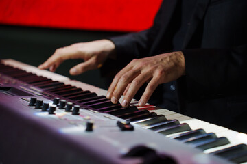 Obraz premium Men's hands play the keys of an electronic piano.